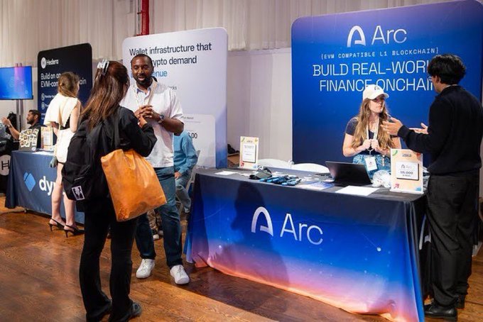 A booth at a blockchain conference showcases "Arc," an EVM-compatible L1 blockchain, with staff engaging attendees and signage promoting the tagline "BUILD REAL-WORLD FINANCE ONCHAIN," directly reinforcing the post's message about bringing real-world finance on-chain.