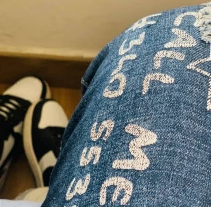 A denim-clad leg with white embroidered lettering rests near black and white sneakers on a wooden floor, capturing a casual Wednesday evening vibe that matches the laid-back, community-appreciating tone of the message celebrating @quipnetwork.