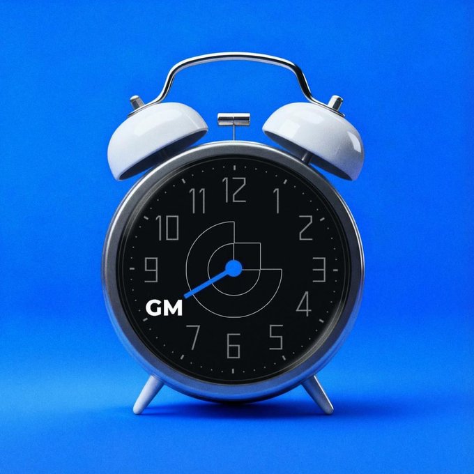 A retro-style twin-bell alarm clock with a black face is displayed against a vibrant blue background, showing the time at approximately 7:43. The clock face features a stylized "GM" logo and lettering, visually reinforcing the post's play on words—suggesting it's "time to gate" or go with GM.