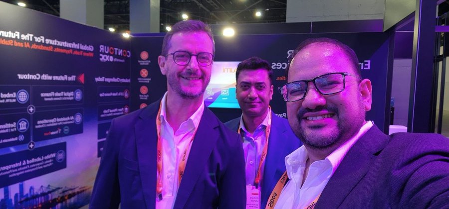 Three men wearing "znipe" lanyards smile for a selfie at the Sibos Miami 2026 conference, posing in front of the Discover Stand DISS43 where Contour, powered by XDC Network, is showcasing digital trade and financial infrastructure innovations.