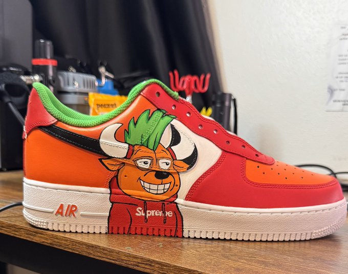 A customized red and orange Nike Air Force 1 sneaker with green trim, featuring a cartoon bull character wearing a red Supreme hoodie as the side graphic design.