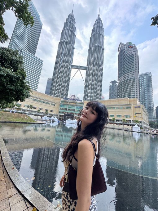 A woman poses for a photo in front of the iconic Petronas Twin Towers in Kuala Lumpur, Malaysia.
