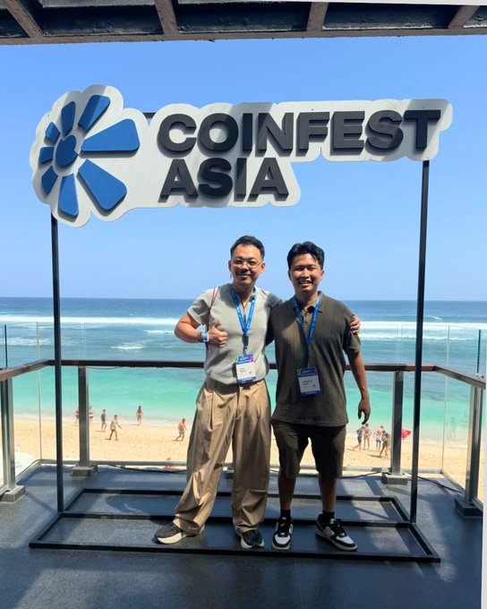 Two attendees pose with arms around each other in front of the large "COINFEST ASIA" sign at a beachside venue, capturing the networking and community spirit highlighted in the post's recap of the conference.