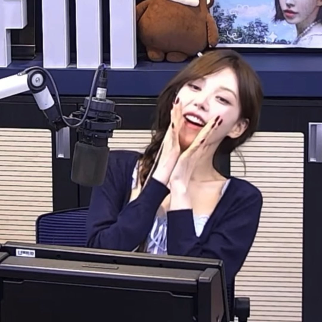 The image shows a woman with brown hair smiling joyfully with her hands on her cheeks, seated in what appears to be a radio studio with a professional microphone. Her cheerful, excited expression complements the post's enthusiastic message about making a fortune, capturing a moment of gleeful optimism.