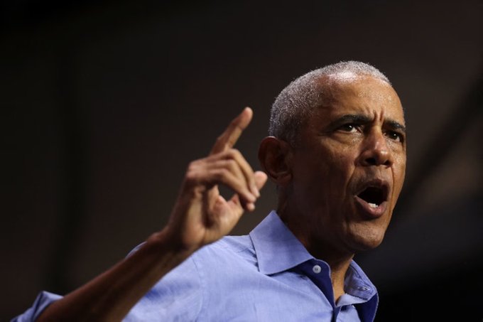 Former President Barack Obama is captured mid-speech, gesturing emphatically with his index finger raised while wearing a light blue button-up shirt. The image pairs with the post's message about statist efforts to ban decentralized AI, using Obama as a recognizable symbol of government authority to underscore concerns about regulatory overreach on emerging technology.