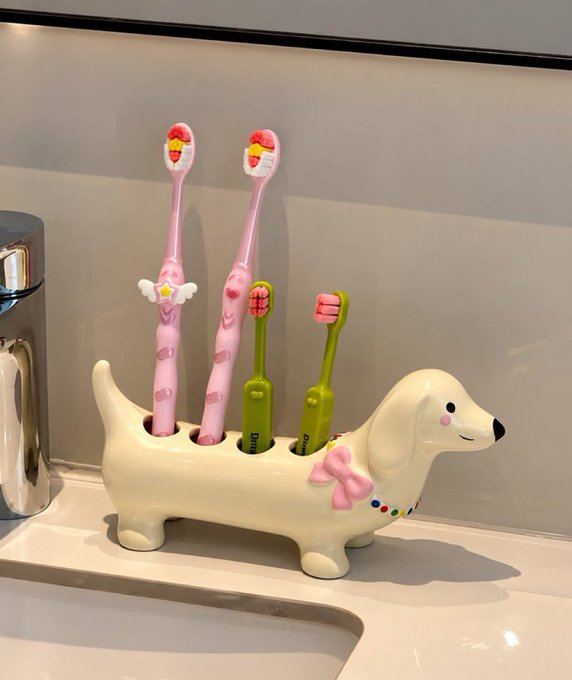 A ceramic dachshund-shaped toothbrush holder holding four colorful toothbrushes sits on a bathroom sink counter.