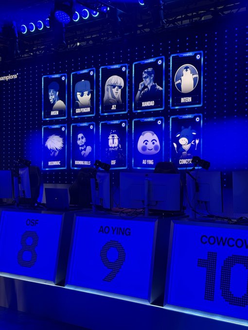 A large screen displays the Champions League lineup of ten competitors (Aisen, Goofyground, Jez, XiaoDao, Inteah, Ursuhinao, Roning Balls, OSF, Ao Ying, Cowc) above numbered player stations 8, 9, and 10, with the caption "Less than 4 hours to go" indicating the countdown to the start of the competition.