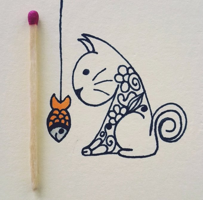 A black ink drawing of a stylized cat with floral patterns next to a matchstick-sized koi fish charm on a string.
