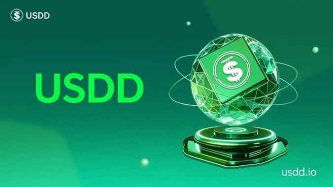 A promotional graphic for USDD cryptocurrency featuring a green holographic sphere with a dollar sign logo, displayed on a podium with the text 'USDD' and 'usdd.io'.