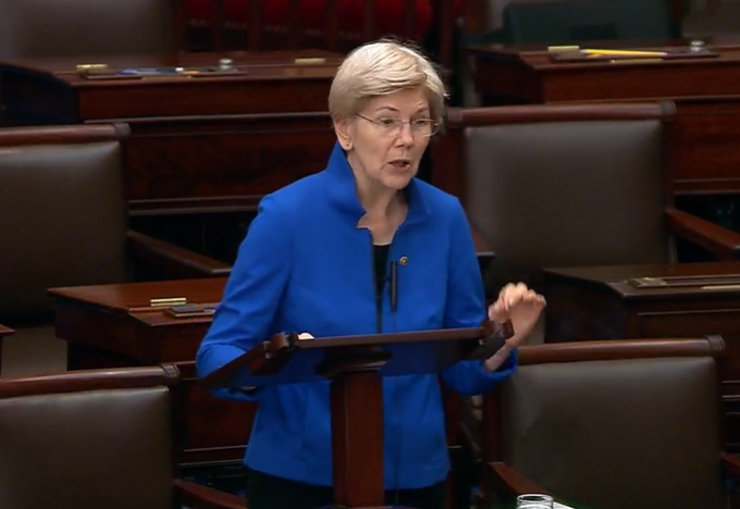 Senator Elizabeth Warren speaks at a podium in what appears to be the Senate chamber, addressing the chamber in a blue blazer, visually representing the "boomer" critique of cryptocurrency regulation described in the caption.