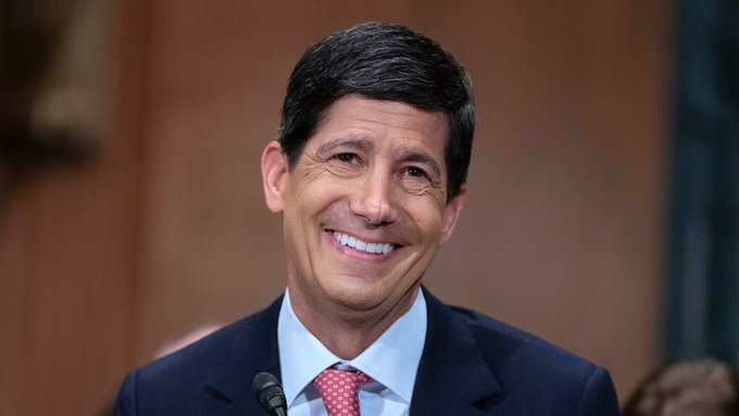 A smiling man in a dark suit and red tie speaks at a microphone, likely during a formal hearing or press event. The image appears to relate to Federal Reserve monetary policy, as the post discusses an $8.633 billion liquidity injection into the US economy and its potential implications for Bitcoin.
