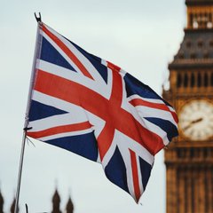 The Union Jack flag waves prominently in front of Big Ben, the iconic London landmark symbolizing Britain's capital. This image directly relates to the FCA's regulatory crackdown on illegal P2P crypto trading in London, representing the UK government's oversight of cryptocurrency businesses within the country.