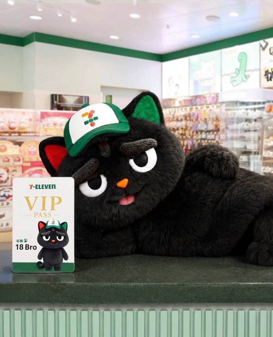 A large black cat plush toy wearing a 7-Eleven cap sitting next to a 'VIP PASS' card for '18Bro' inside a 7-Eleven store.