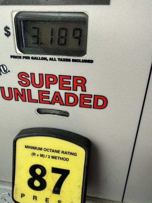 The image shows a gas station pump display with the words "Super Unlaced" written above the current amount of gas being pumped, which is 87 cents per gallon. At least two people are shown in this scene as well; one person presumably paying for the fuel and another potentially being a customer using the machine to pay.