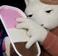 A small, low-resolution clip of a white, fluffy cartoonish cat-like puppet or plush toy wearing a pink backpack or garment.