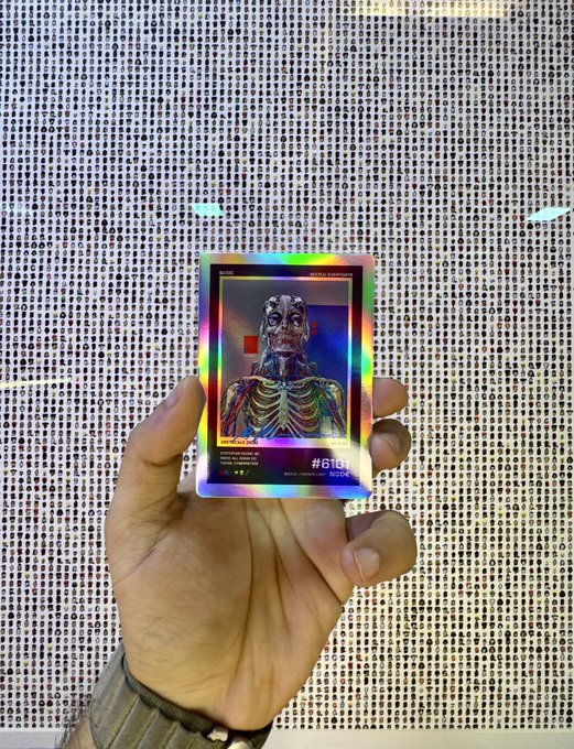 A hand holds a holographic Beeple card numbered #6103/10000, featuring a metallic skeletal figure design. The card's iridescent sheen and limited-edition appearance align with the post's claim of it being a rare "Triple Error Beeple Card" with only 3 in existence (vaulted 1/3).