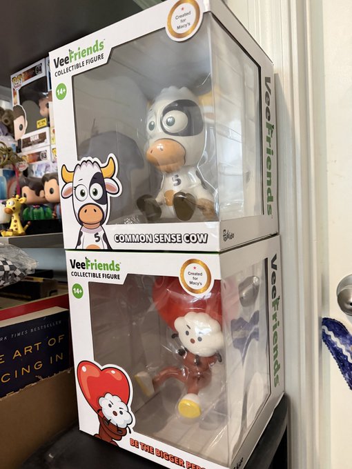 Two packaged 'VeeFriends' collectible figures by Gary Vaynerchuk, stacked on top of each other, featuring a cow and a red character holding a heart.