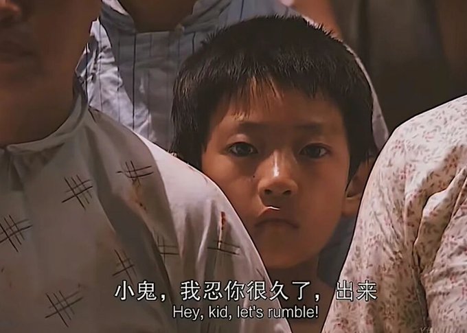 A young boy with a serious expression peers out from behind two adults, with the subtitle "小鬼，我忍你很久了，出来 / Hey, Kid, let's rumble!" displayed at the bottom of the image.