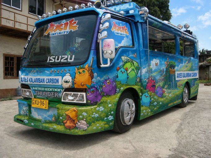 A vibrantly painted "Axle Infinity" themed Isuzu bus, labeled "Limited Edition Thunder" and "Axles Kalamban Carbon" with license plate GXU-961, is parked on a street, ready to whisk "boys and girls" away to its next stop, Lunacia.
