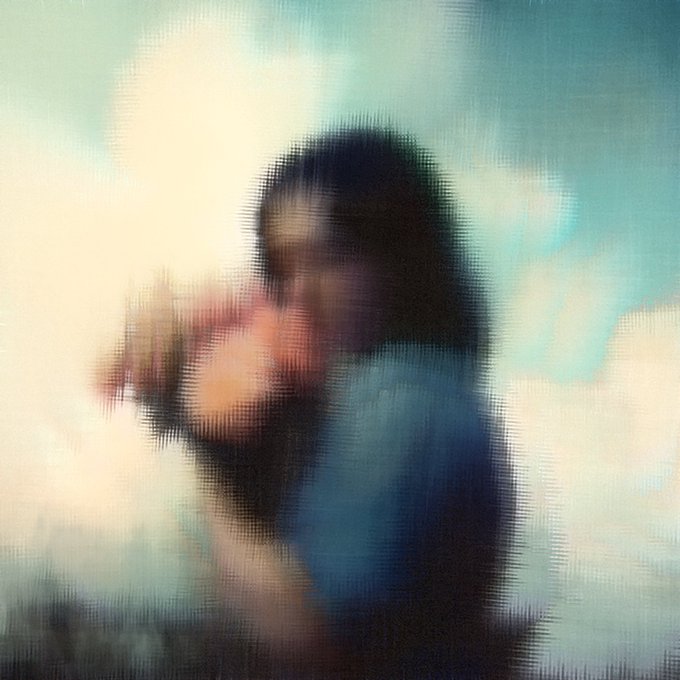 Heavily blurred/distorted image of a person holding a camera against a light teal and white background.