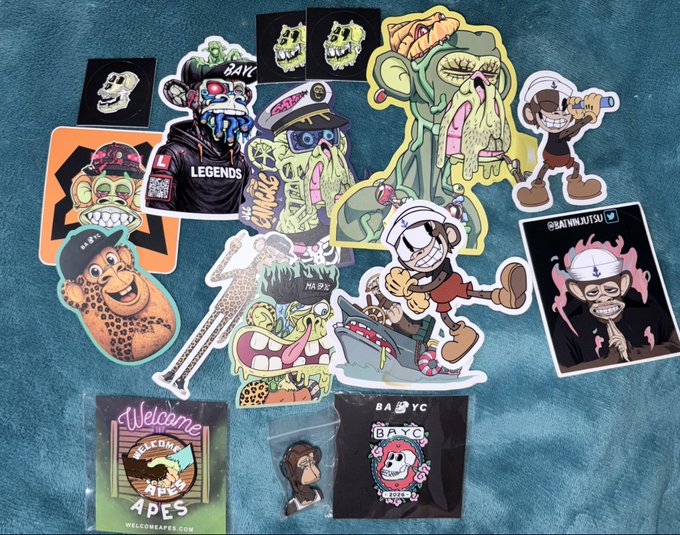 A collection of colorful stickers featuring cartoon-style illustrations of monkeys, monsters, skulls, and characters is scattered across a blue textured surface.