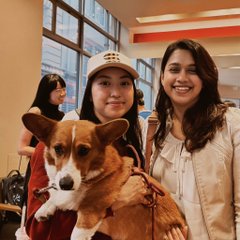 The image features two women standing next to a brown dog, both smiling for the camera. The woman on the left has her arm around the dog's neck, while the other woman stands behind them with her hand on her hip. In the background, there are three more people who appear to be in conversation or observing something else. The post includes text that reads "400 founders @solana summer SF and @trudythecorgi closed the most deals".