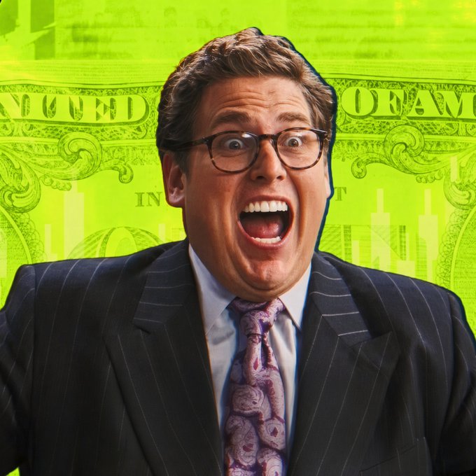 A man in a pinstripe suit and glasses with an exaggerated shocked expression against a bright green background featuring currency design elements.