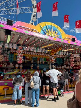 A crowd gathers at a carnival booth displaying rows of Pudgy Penguin plush toys as prizes, with the accompanying post highlighting that each plush is officially licensed from the Pudgy Penguins NFT collection, suggesting mainstream crossover success.