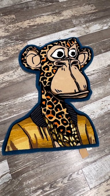 A plush toy shaped like a giraffe in a military uniform lies on a wooden floor.