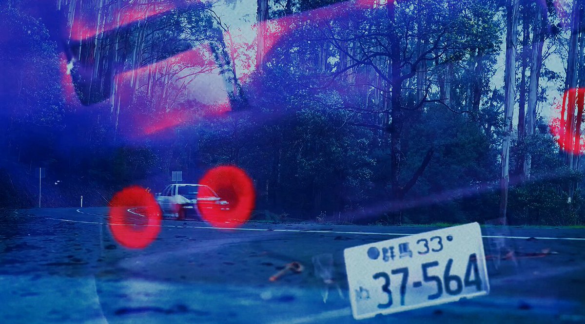 The image features a close-up of an old license plate with the numbers 37-654 visible. The background shows a forested area, suggesting that this photo was taken at a location near trees or woods. The caption provided by the image is related to the famous car "AE86" and its impact on modern culture.