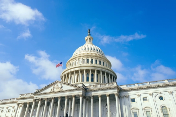 The image shows the U.S. Capitol Building with its iconic dome and an American flag against a blue sky, symbolizing the legislative process mentioned in the post about the Senate's failure to advance the Crypto CLARITY Act and the uncertainty over whether Congress or regulators (Atkins and Selig) will shape crypto policy next.