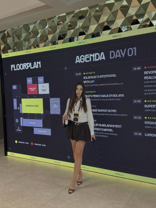 A woman stands in front of a large digital display showing the 'AGENDA DAY 01' floorplan and schedule for a Solana Breakpoint event, with sessions like 'SOLANA GETS INTENTIONAL WITH LI.FI' and 'RWA SYNERGY'.