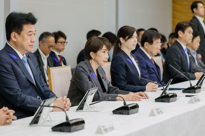 A group of Japanese officials, likely politicians, are seated at a table during a meeting, illustrating the growing emphasis on AI development compared to crypto.
