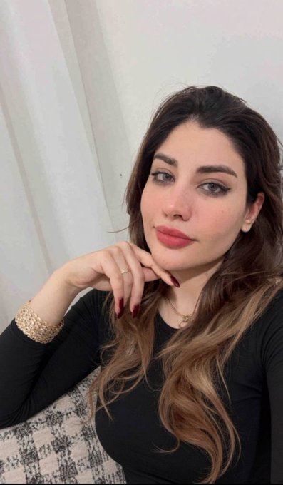 A woman with long brown hair poses thoughtfully with her hand near her chin, wearing a black top, gold bracelet, and delicate necklace, capturing a poised "good morning" vibe. Her calm, confident expression perfectly complements the uplifting "GM CT" greeting.