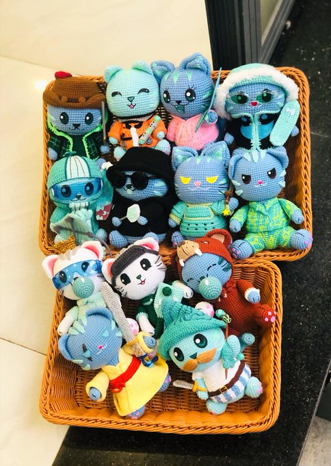 The image features a basket filled with various stuffed animals, including teddy bears of different colors and sizes. Some of them appear to be wearing costumes or outfits that make them look like characters from movies or TV shows. The scene suggests that these toys are being prepared for display or storage in their new home.