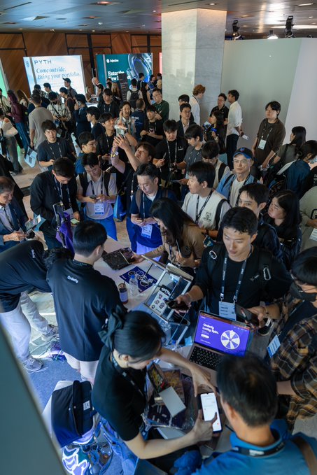 Crowds swarm the Orderly booth at KBW, with attendees gathered tightly around a display table featuring laptops and promotional materials as staff engage with visitors. Visible signage reads "Come outside, better your portfolio," highlighting the strong interest in perpetual futures trading at the busy event.