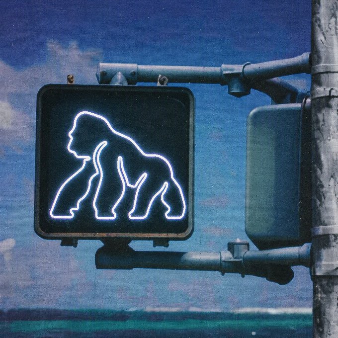 A neon gorilla crossing sign mounted on a pole, which visually represents the "$APE" ticker mentioned in the post.