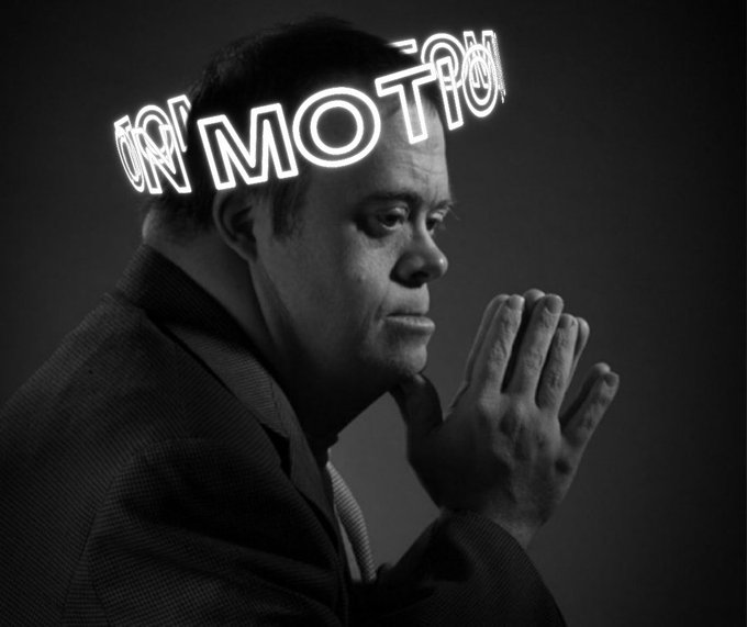 A black and white photo of a man in a suit with his hands clasped, overlaid with neon-style text reading 'NO MOTION'.