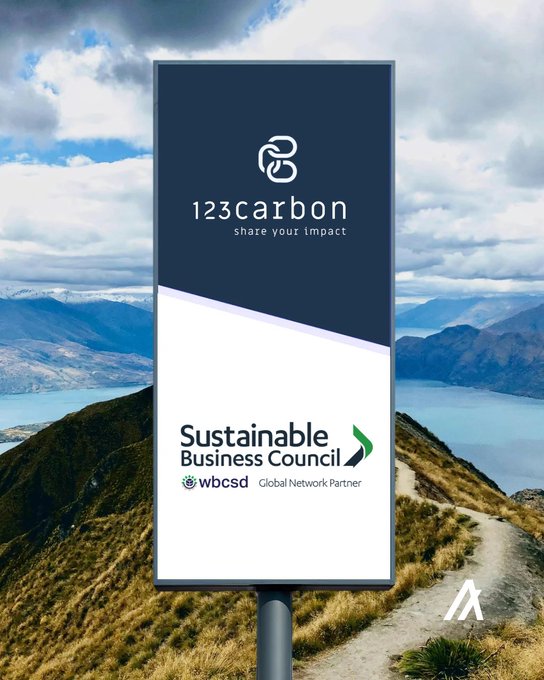 An outdoor billboard for 123carbon displaying 'share your impact' alongside a Sustainable Business Council and WBCSD Global Network Partner logo, set against a mountain landscape.
