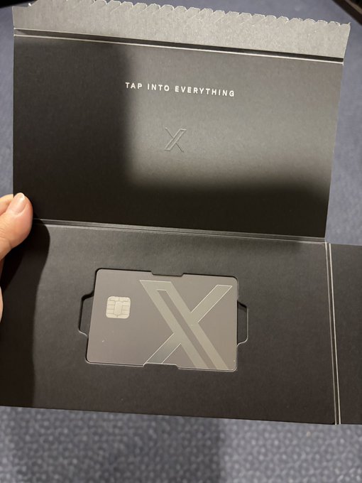 An open black package displaying the text 'TAP INTO EVERYTHING' with a metallic card featuring a large 'X' design inside.
