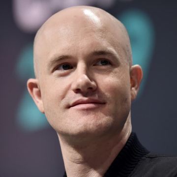 A bald man in a dark sweater smiles slightly against a blurred background. The image accompanies a post about Coinbase CEO Brian Armstrong discussing regulatory clarity in the crypto industry.