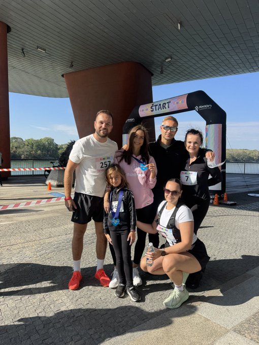 A group of six participants pose at the "START" line of a charity run, with bib numbers 257 and visible, marking QORPO's inaugural charity run for the TAMITOS children's brand.