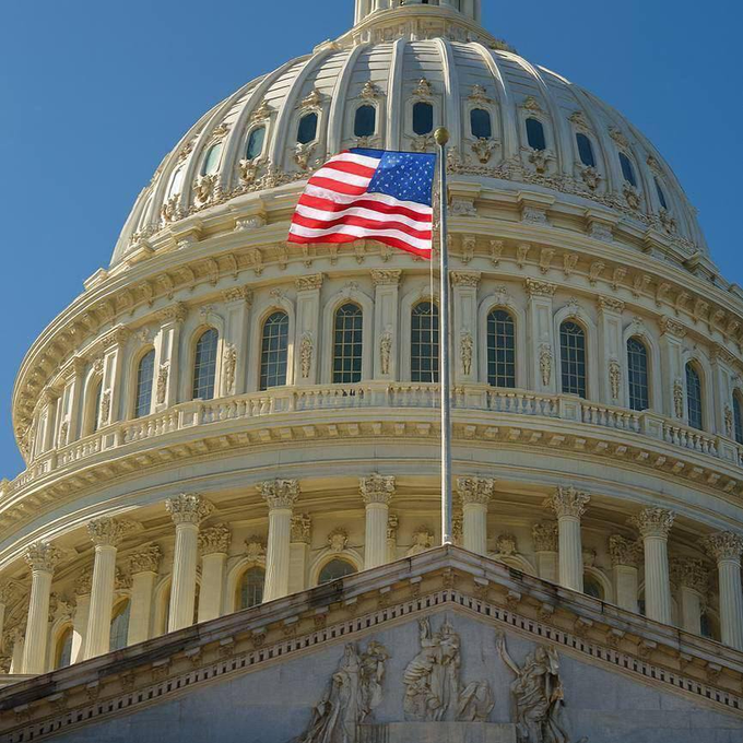 The United States Capitol Building is shown with the American flag flying in front of it. This image visually represents the legislative body, the Senate, which has 15 days to pass the Crypto Clarity Act.