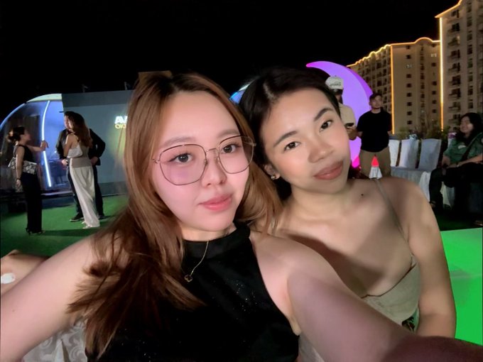 The image features two women posing for a picture together, both wearing black tops and glasses. They are standing next to each other with their arms around each other's shoulders, creating an intimate atmosphere. The background of the photo shows a building, suggesting that they might be at an event or gathering in an urban setting. 

The caption "With the prettiest @enshielada" is likely meant to be humorous and playful, as it refers to one of the women wearing glasses. This adds a lighthearted touch to the image while still capturing the essence of their friendship and shared experience.