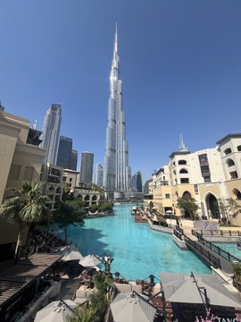 The Burj Khalifa towers over a turquoise waterway lined with umbrellas and Middle Eastern-style architecture in downtown Dubai. The image showcases the iconic Dubai skyline, fitting the post's invitation to web3 enthusiasts to connect in the city through Arts DAO.