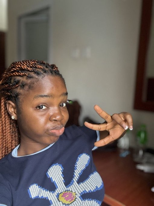A young woman with braided hair poses indoors, making a peace sign with her hand, wearing a navy blue t-shirt featuring a sparkling daisy design. The image accompanies a cheerful "Good Morning CT" message welcoming a new month with motivational energy, fitting the upbeat and positive tone of the post.