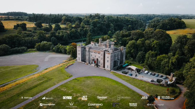 An aerial view shows a large stone castle surrounded by green fields and trees, with various cryptocurrency project logos displayed at the bottom including Skyrise, Jet, Seeker, Jito, Solana Foundation, and others.