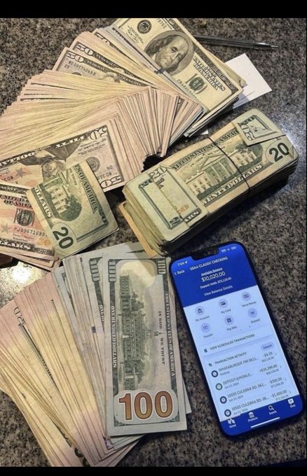 A phone displays a Charles Schwab account balance of $10,020.00, surrounded by several hundred-dollar bills, bundles of twenty-dollar bills, and additional loose currency spread across a granite surface. The image visualizes the caption "Manifest! I know you'll be rich!" by pairing a visible account balance with stacks of cash to symbolize achieved financial abundance.