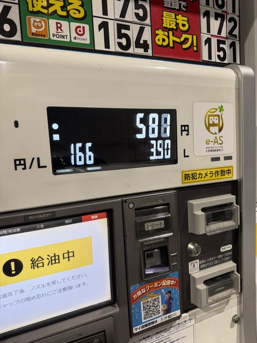 Japanese self-service gas pump displaying fuel prices of 175 and 154 yen with digital readout showing 588 yen for 3.90 liters, with e-AS loyalty card slot and security camera notice.