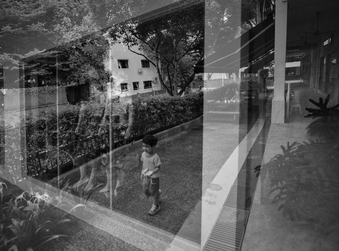 A young boy walks through a courtyard, his ghostly reflection doubled in the glass as the multi-exposure technique blends two moments into one ethereal, dreamlike frame. The black-and-white composition, titled "Find Your Way Back," evokes a sense of memory and searching, echoing the artwork's edition details of 15 prints at 5 XTZ.